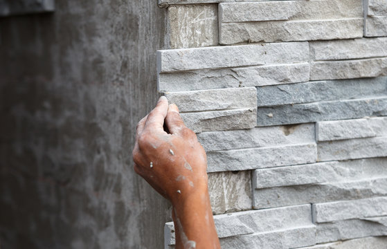 worker install stone wall surface with cement for house