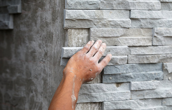 worker install stone wall surface with cement for house