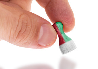 Hand holding wooden pawn, flag painting, selective focus