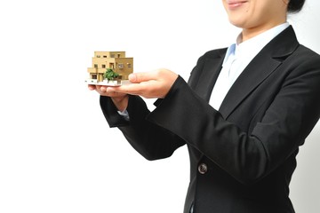 家を紹介するスーツのアジア人女性