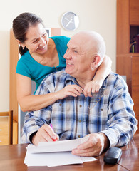 Obraz premium Happy mature couple fills in paper documents