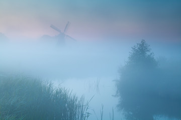 windmill silhouette in dense sunrise fog