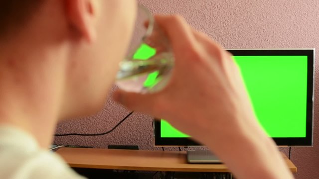 Man watches TV(television) - green screen - man drinks water