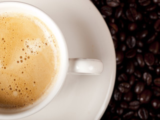 Top view of a cup of dark roasted coffee with coffeebeans