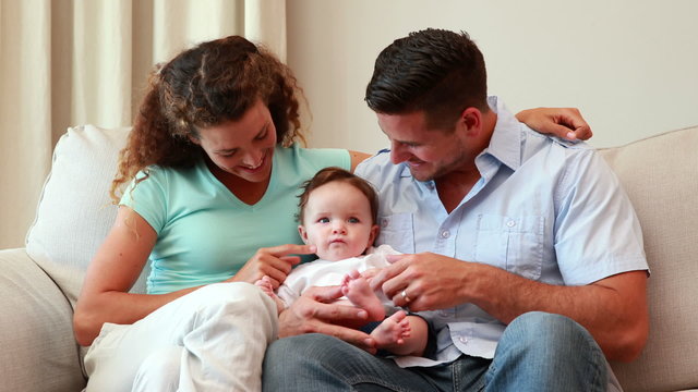 Young parents sitting on the couch with their baby son
