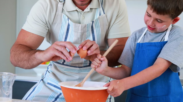 Smiling father and son making a cake together