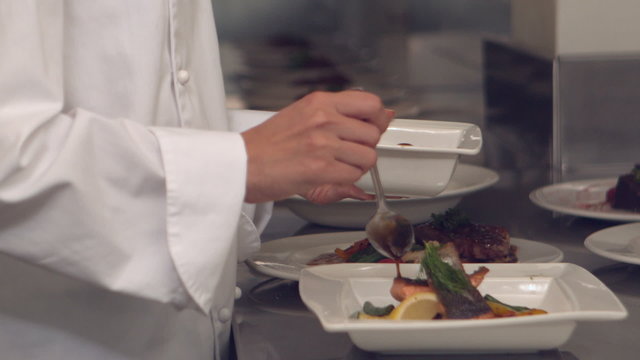 Chef pouring sauce over fish dish