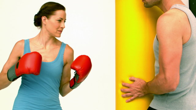 Fit woman punching a bag held by trainer