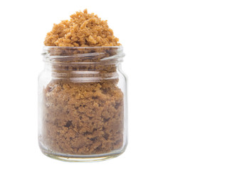 Grated Coconut sugar in a glass container over white background
