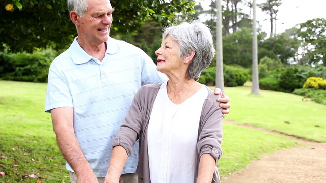 Retired couple standing in the park together with woman on a bik