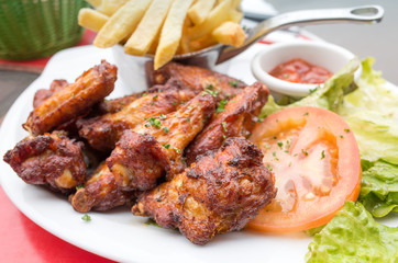 Chicken wings with sauce and golden French fries