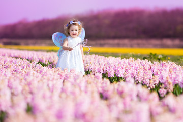 Beautiful toddler girl in fairy costume in a flower meadow
