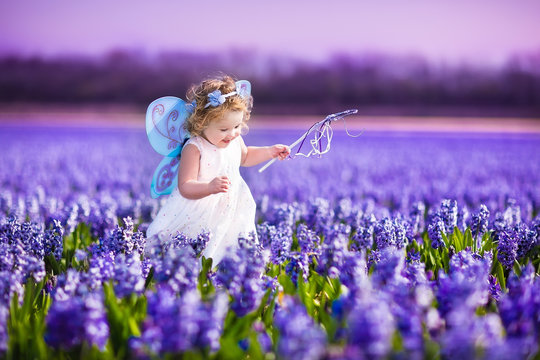 Adorable toddler girl in fairy costume in a flower field