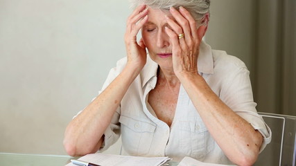 Senior woman sitting at table working out bills