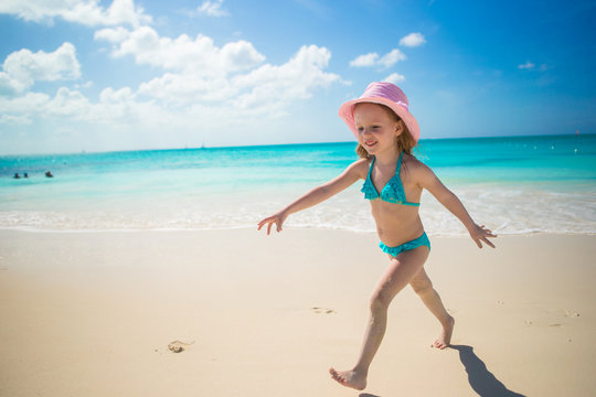 Little girl running along the beach and enjoy summer holidays