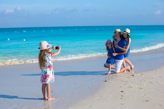 Little Girl Making Photo On Phone Of Her Family At The Beach