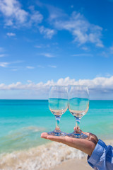 Closeup of two wineglasses in a man's hand on the white sandy