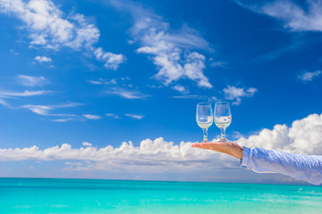 Fototapeta premium Two clean glasses at male hand on blue sky background