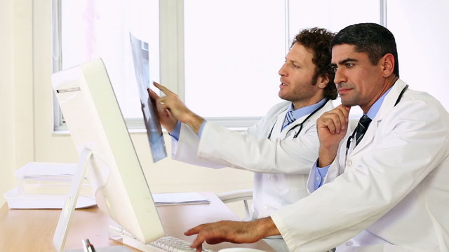 Doctors sitting at desk talking about xray