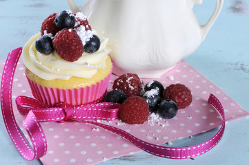 Delicious cupcake with berries on shabby chic table