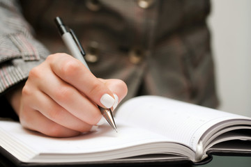 Female hand writing in notebook