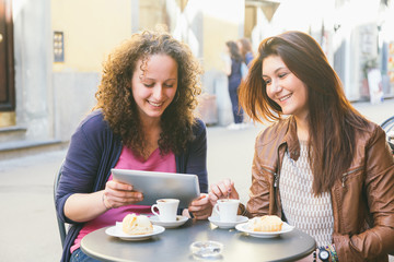 Girls Using Digital Tablet while Having Breakfast