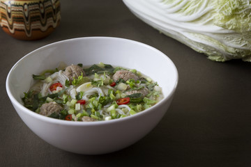 Thai noodle soup with meatballs, Chinese cabbage and cilantro
