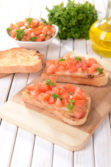 Delicious bruschetta with tomatoes on cutting board close-up