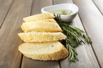 Fresh bread with olive oil and rosemary on wooden table
