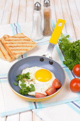 Scrambled eggs and bacon on frying pan on table close-up