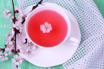 Fragrant tea with flowering branches on wooden table close-up