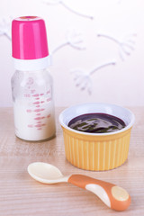 Baby food and milk on table on light background