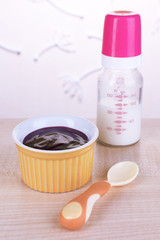 Baby food and milk on table on light background