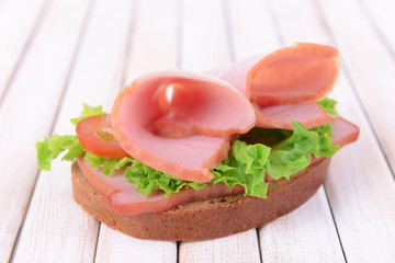 Delicious sandwich with lettuce and ham on table close-up