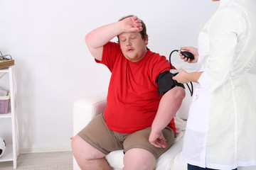 Doctor examining  patient obesity on light background - obrazy, fototapety, plakaty