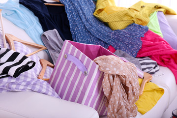 Messy colorful clothing on  sofa on light background