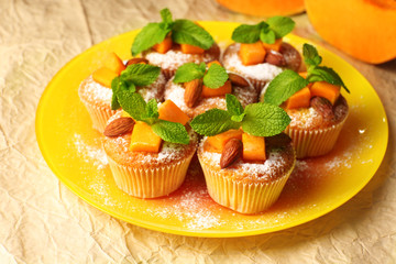 Tasty pumpkin muffins on brown paper