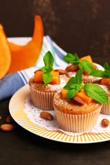 Tasty pumpkin muffins on wooden table