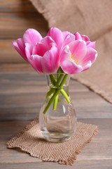 Beautiful tulips in bucket in vase on table on grey background