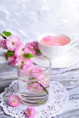 Fototapeta na wymiar Beautiful fruit blossom in glass on table on grey background
