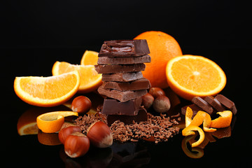 Chocolate, orange and  hazelnuts on black background