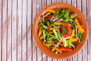Beef salad on plate on wooden background