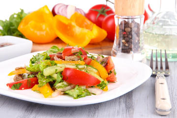 Beef salad on plate with vegetables and spices on wooden table