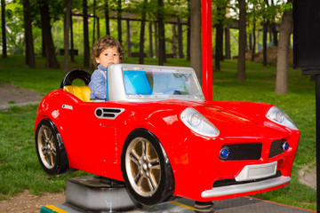 Toddler boy having fun in a car in park