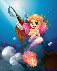 Obraz na płótnie Canvas A pretty mermaid under the sea near the rocks