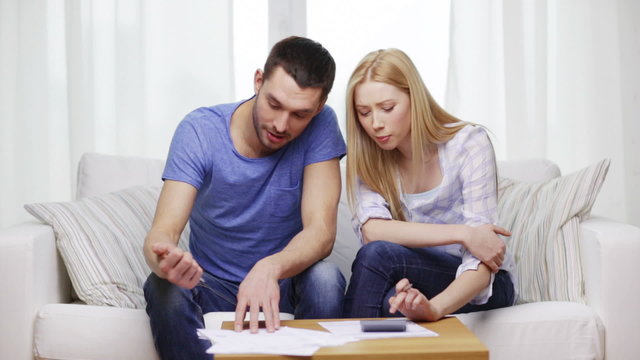 busy couple with papers and calculator at home