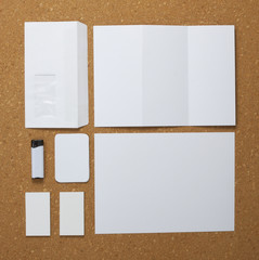 White collection of stationery on corkboard background.