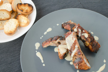 Spareribs on grill with dip and toasted baguette