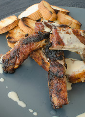 Spareribs on grill with dip and toasted baguette