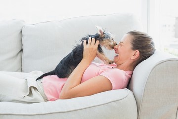 Happy woman playing with her yorkshire terrier on the couch